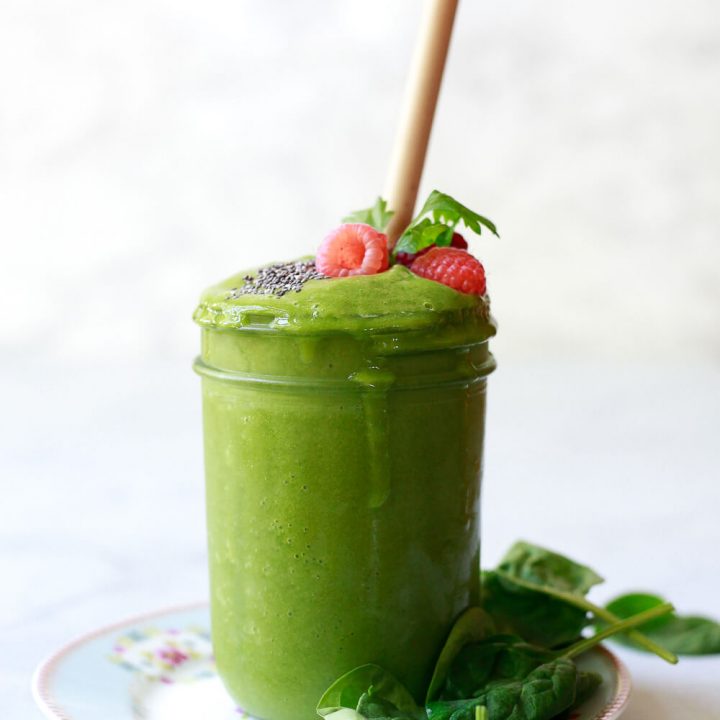 A green detox smoothie in a glass jar with bamboo straw.