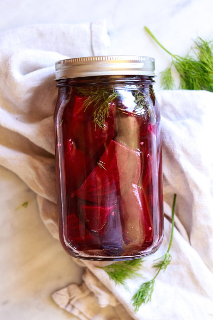 A beautiful jar of pickled beetroot on a marble countertop.