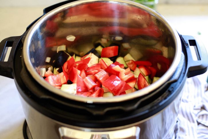 Red bell peppers, eggplant, and onions in an Instant Pot to make ratatouille. 