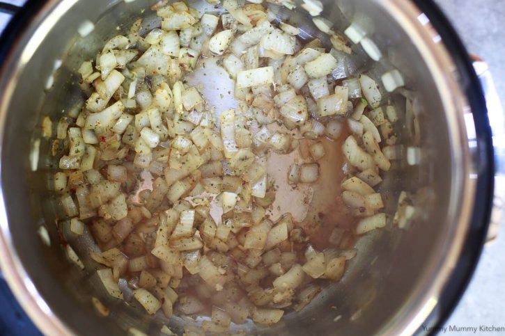 Onions, garlic, and spices saute in an Instant Pot to start making Instant Pot spaghetti sauce. 