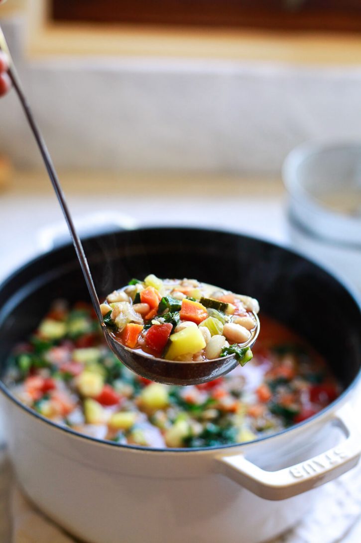 Photo of a ladle scooping up Italian vegetable soup. 