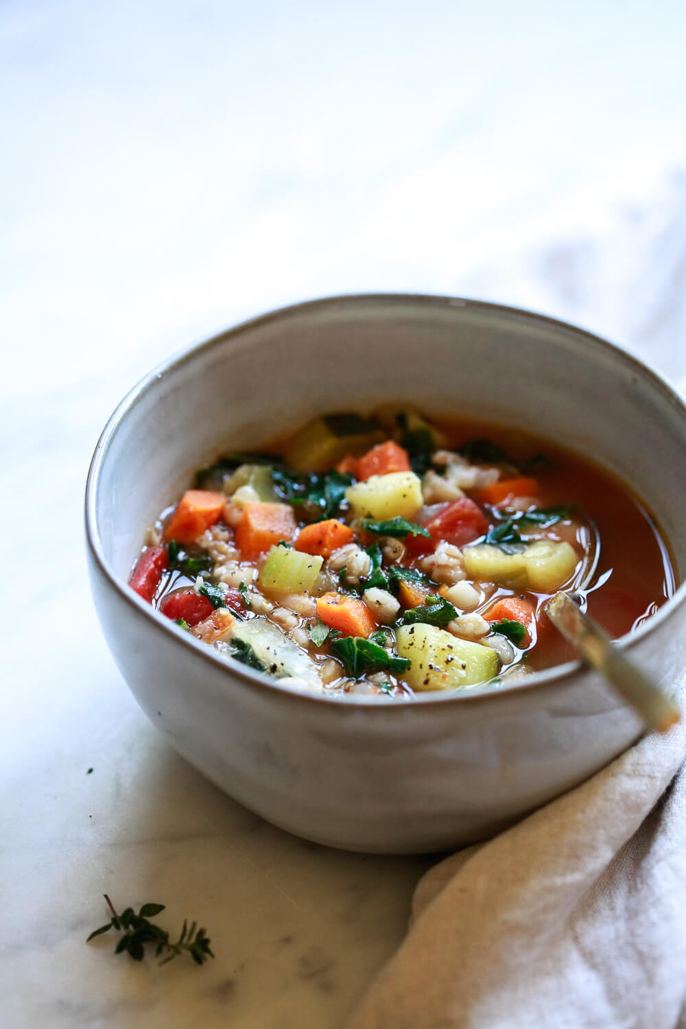A grey ceramic bowl filled with an Italian vegetable soup with farro. 