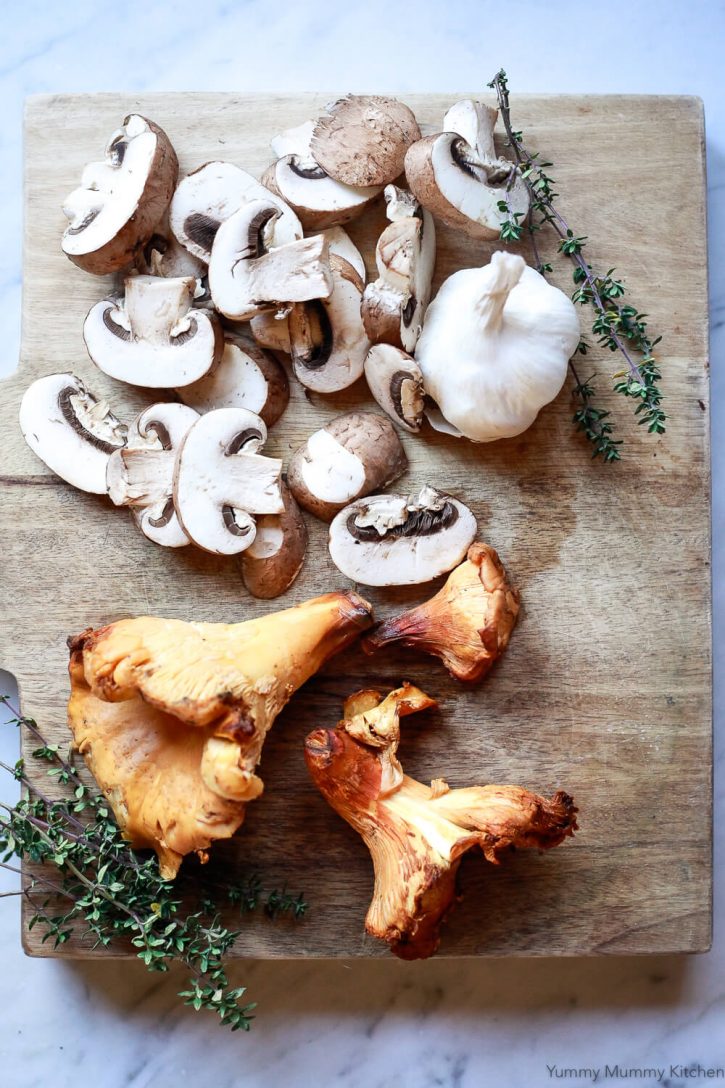 Wild Chanterelle mushrooms, Baby Bella mushrooms, garlic, and thyme on a cutting board before making farro risotto. 