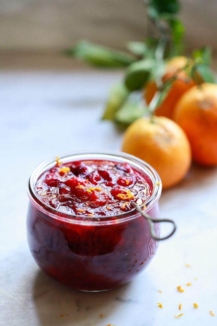 A Weck jar filled with homemade cranberry sauce recipe and topped with orange zest. 