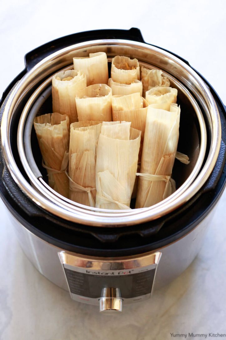 Tamales sit in the steamer basket of an Instant Pot pressure cooker ready to steam. 