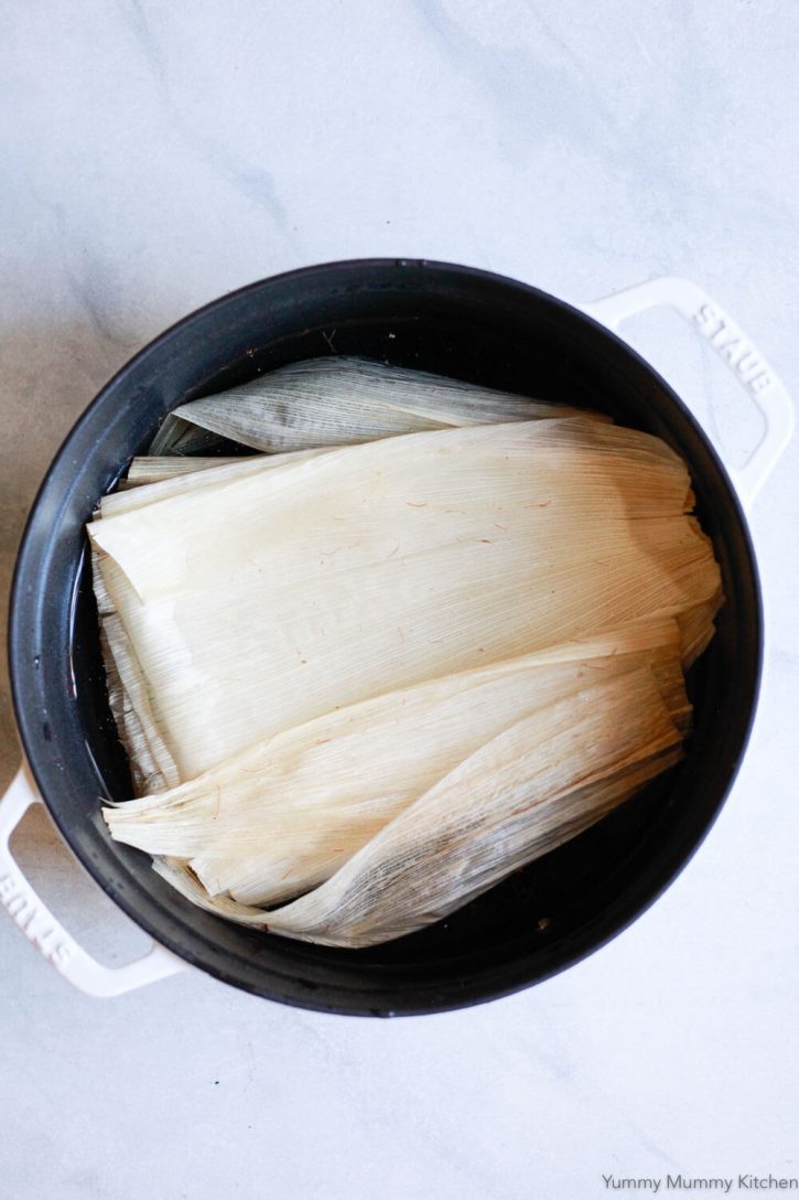 Corn husks soak in a large pot to prepare for making tamales. 