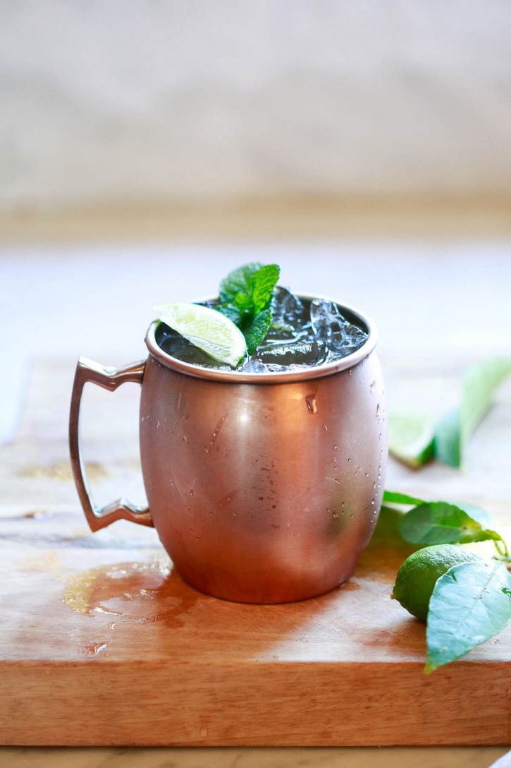A virgin Moscow Mule ginger beer mocktail in a copper mug with ice on a kitchen counter. 