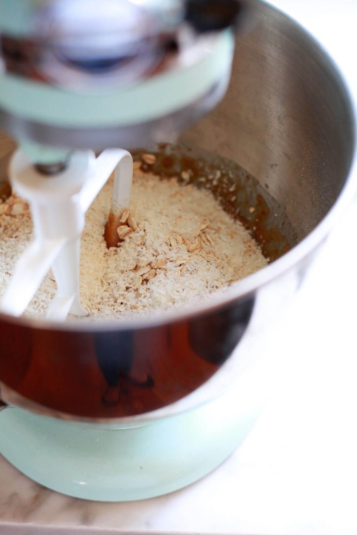 Dry ingredients are added to wet ingredients when making vegan cookies in a KitchenAid mixer. 