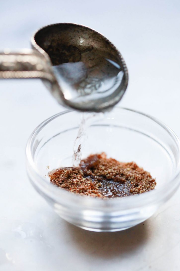A tablespoon of water is poured into a bowl of flax meal to make a vegan flax egg. 