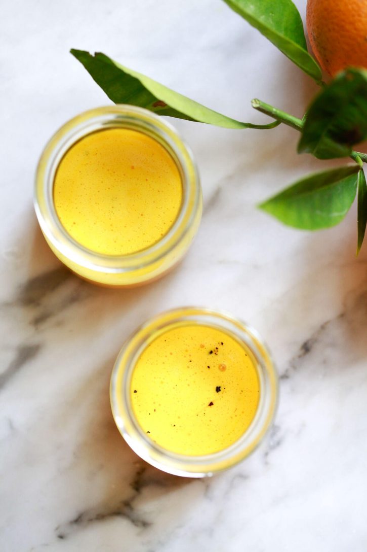 A simple turmeric shot recipe and turmeric shot benefits. Two homemade turmeric shots on a marble kitchen counter. 