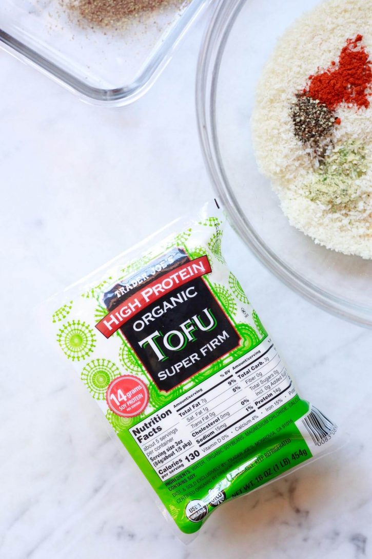 A block of Trader Joe's high protein organic super firm tofu sits on a countertop next to panko breadcrumbs for making tofu nuggets. 