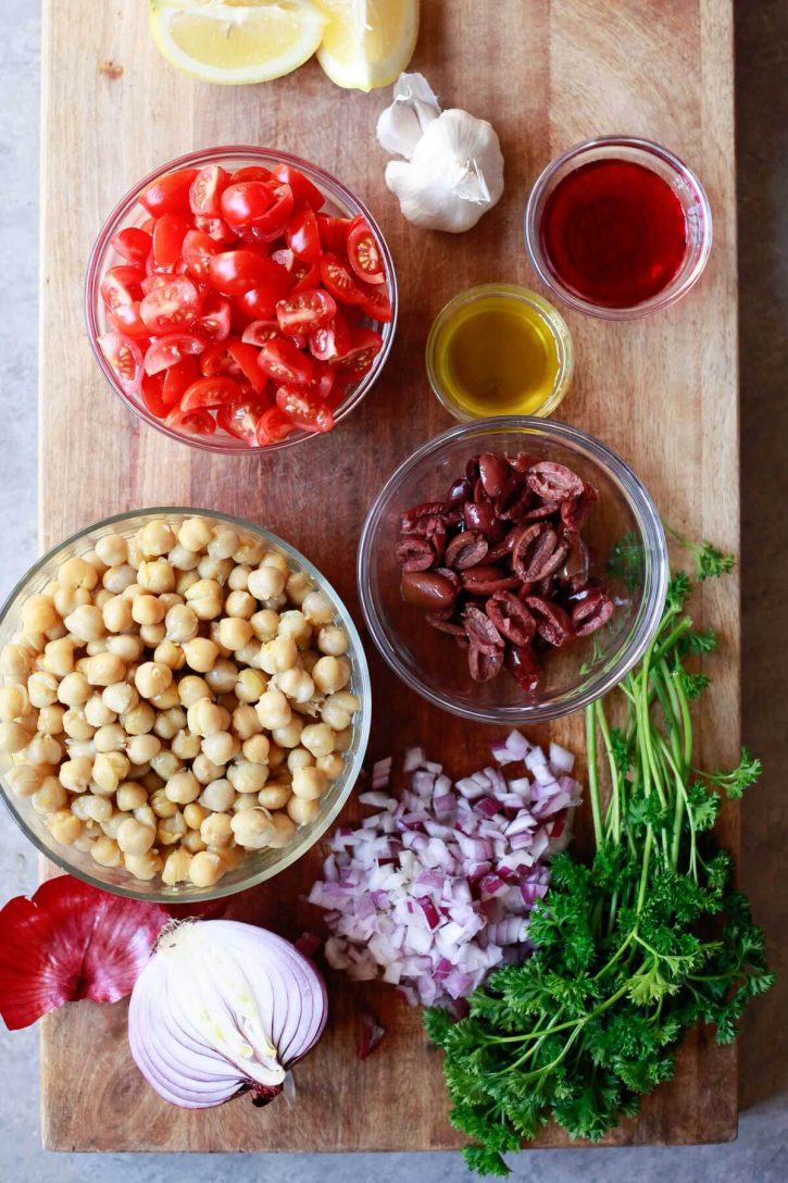The ingredients for Balela, a Middle Eastern bean salad, in bowls on a cutting board. 