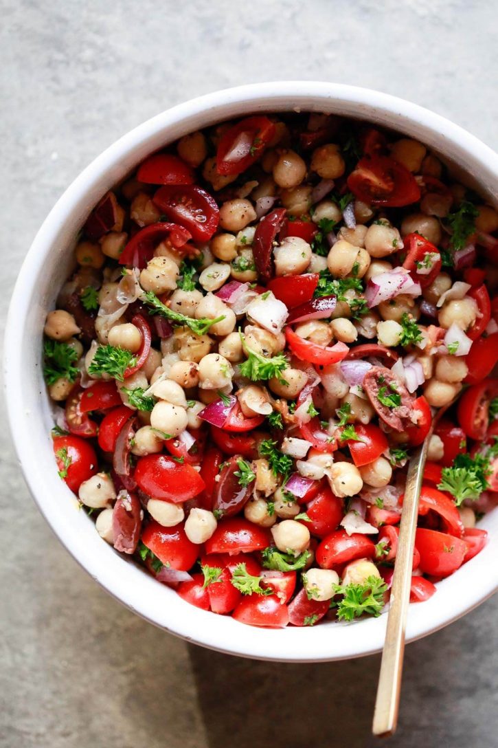 A white bowl filled with Balela, a Middle Eastern chickpea and bean salad with tomatoes, herbs, olives, and onions. A healthy vegetarian, vegan, gluten free recipe. 