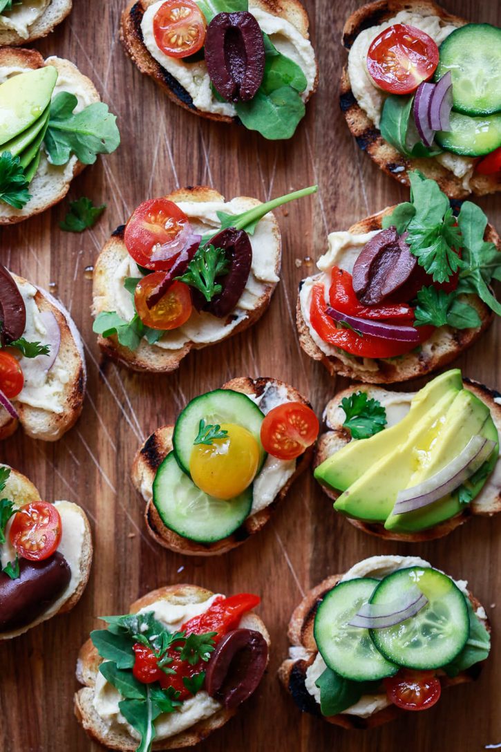 A close-up of beautiful healthy crostini appetizers topped with Mediterranean ingredients. These crostini are the best easy and delicious vegetarian vegan appetizers. 