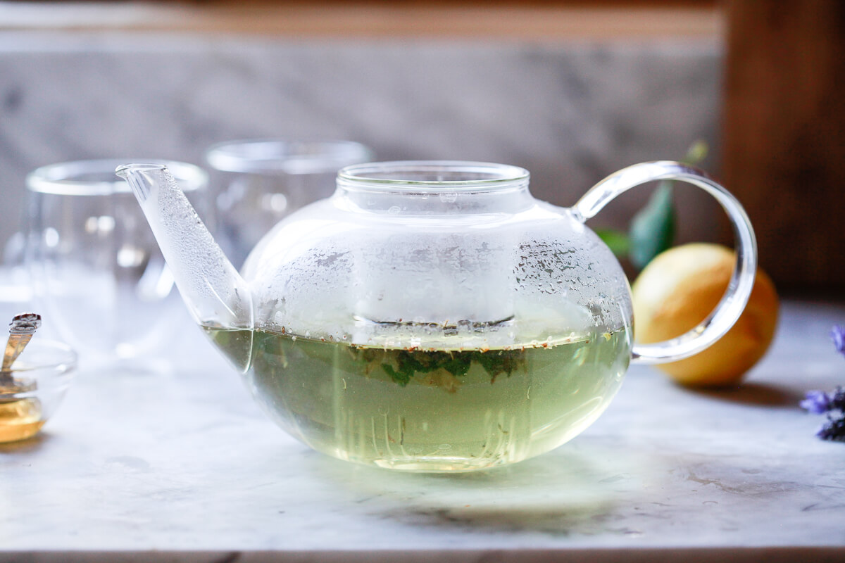 Lavender tea steeps in a glass teapot.