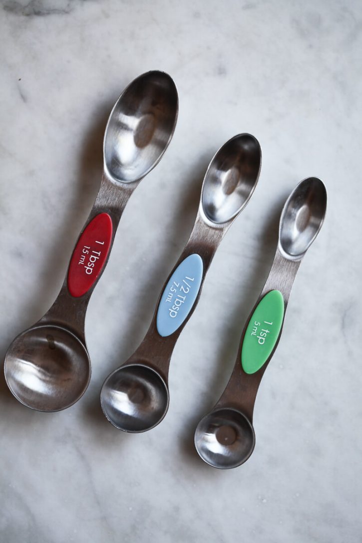 A teaspoon, half teaspoon, and tablespoon sit on a counter to show the size difference. 