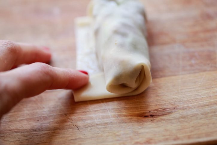 An egg roll wrapper is rolled around filling. 