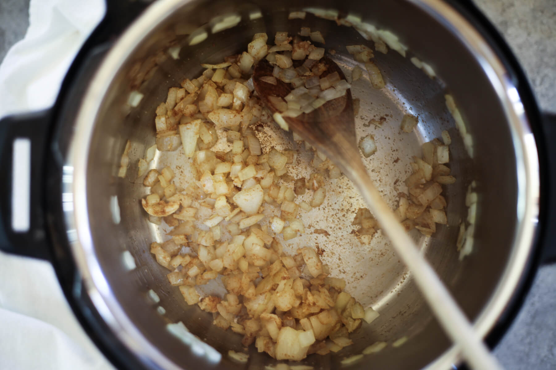 Onions, garlic, cumin, and salt cook in the bottom of an Instant Pot.