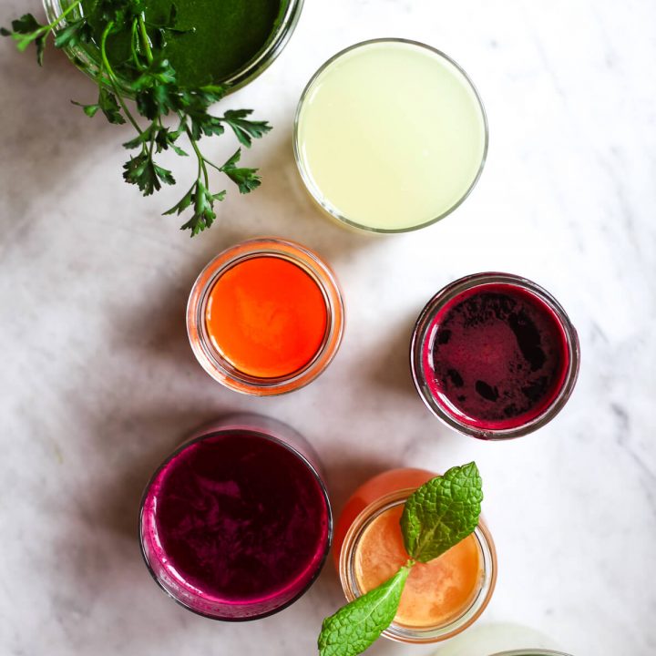 Six glasses of colorful freshly pressed juices.
