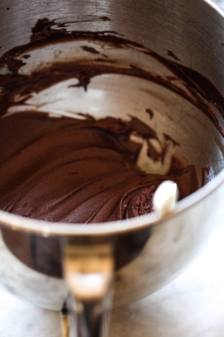 A silver mixing bowl filled with homemade vegan chocolate frosting. 