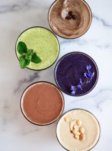 5 different protein shakes on a marble countertop.