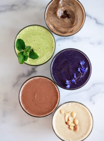 5 different protein shakes on a marble countertop.