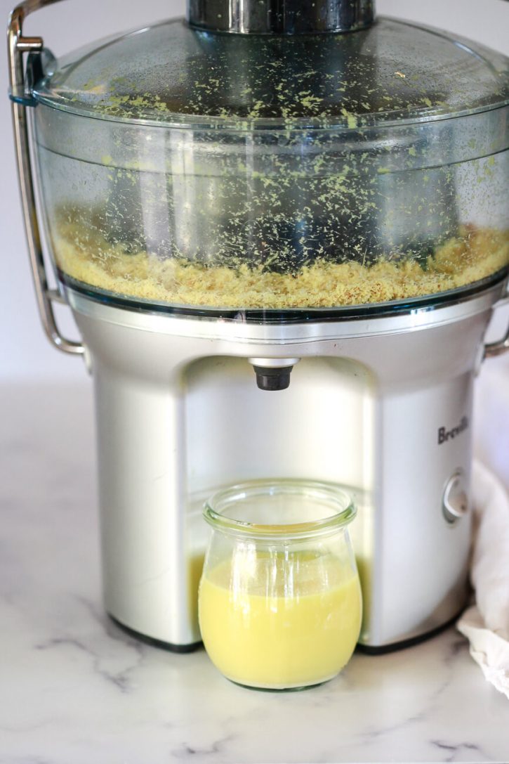 A Breville juicer juices fresh ginger into a small jar. 