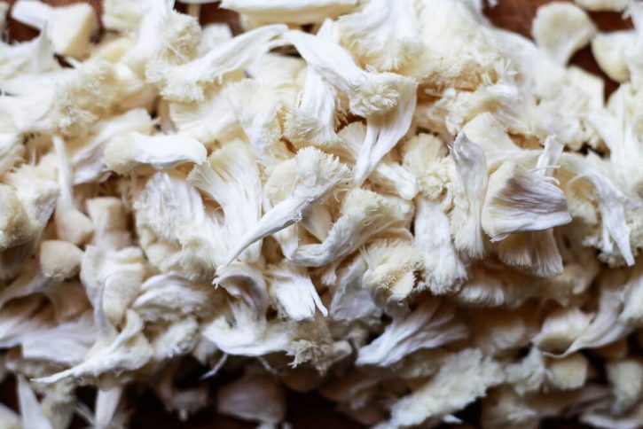 A close-up photograph of shredded or pulled lion's mane mushroom. 