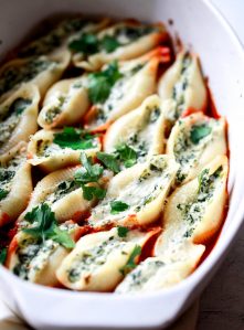 A white casserole dish filled with ricotta and spinach stuffed jumbo shell pasta.