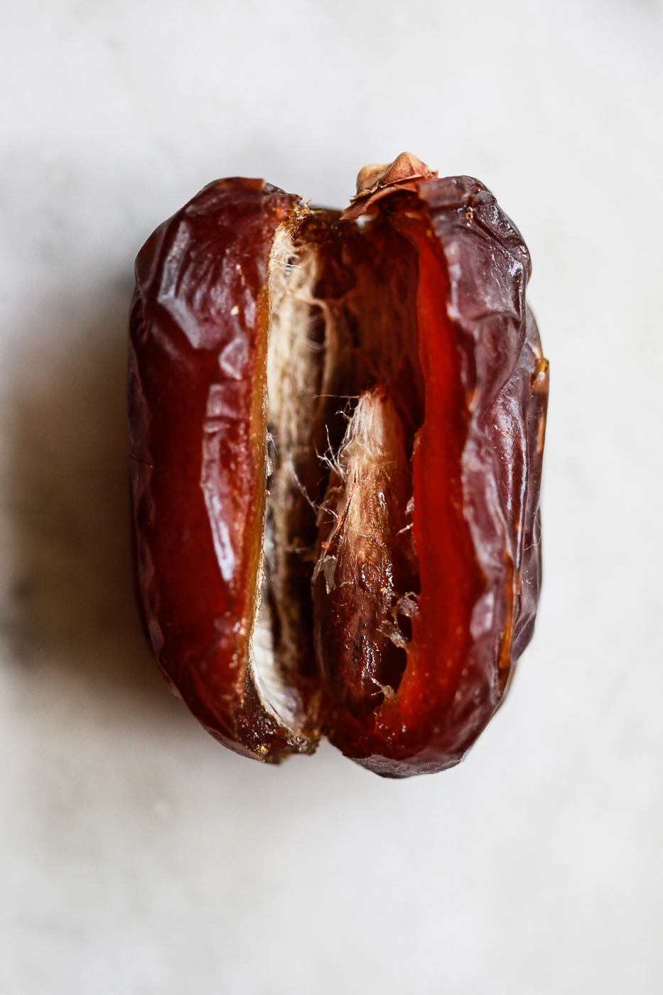 A macro photo of one Medjool date cut open to reveal the pit. 