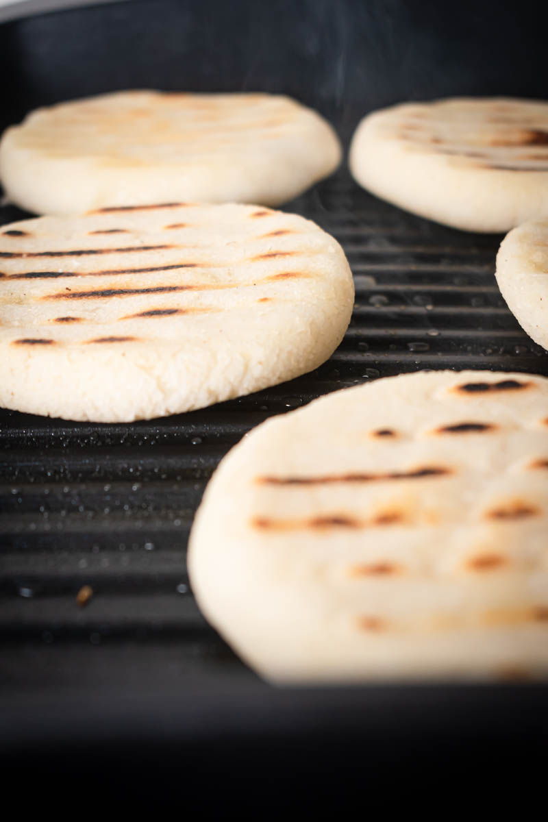 Arepas Venezolanas are grilled on a grill pan.