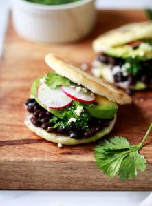 Close-up photo of an arepa filled with black beans, cheese, and avocado.