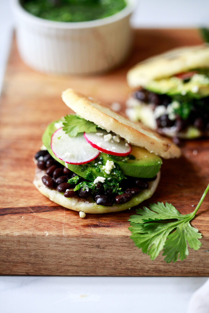 Close-up photo of an arepa filled with black beans, cheese, and avocado.
