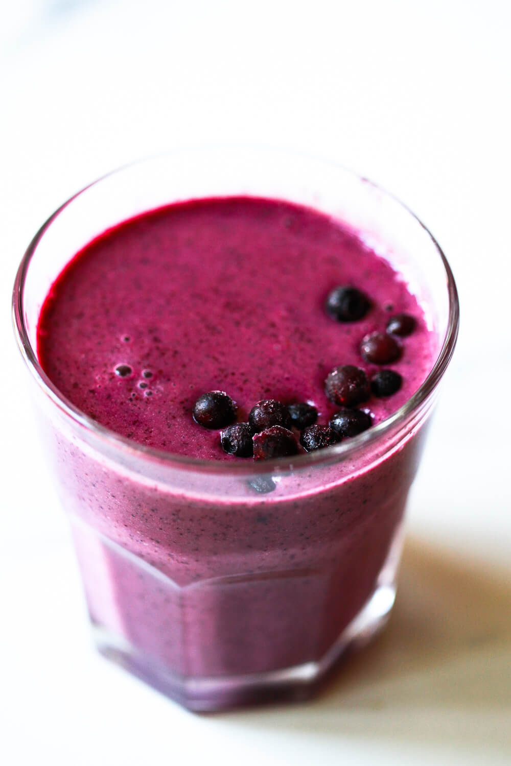 A beautiful purple blueberry pomegranate smoothie in a glass.