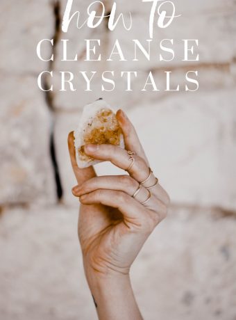 A hand holds up a yellow crystal. White text overlay reads, "how to cleanse crystals"