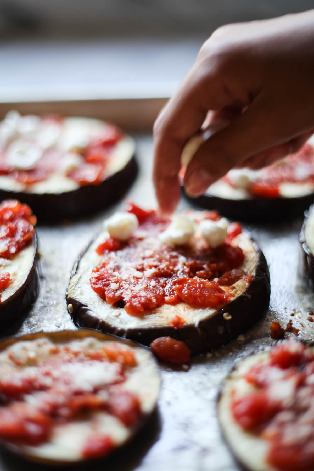 Baked eggplant rounds are topped with sauce and cheese to make mini eggplant pizzas. 