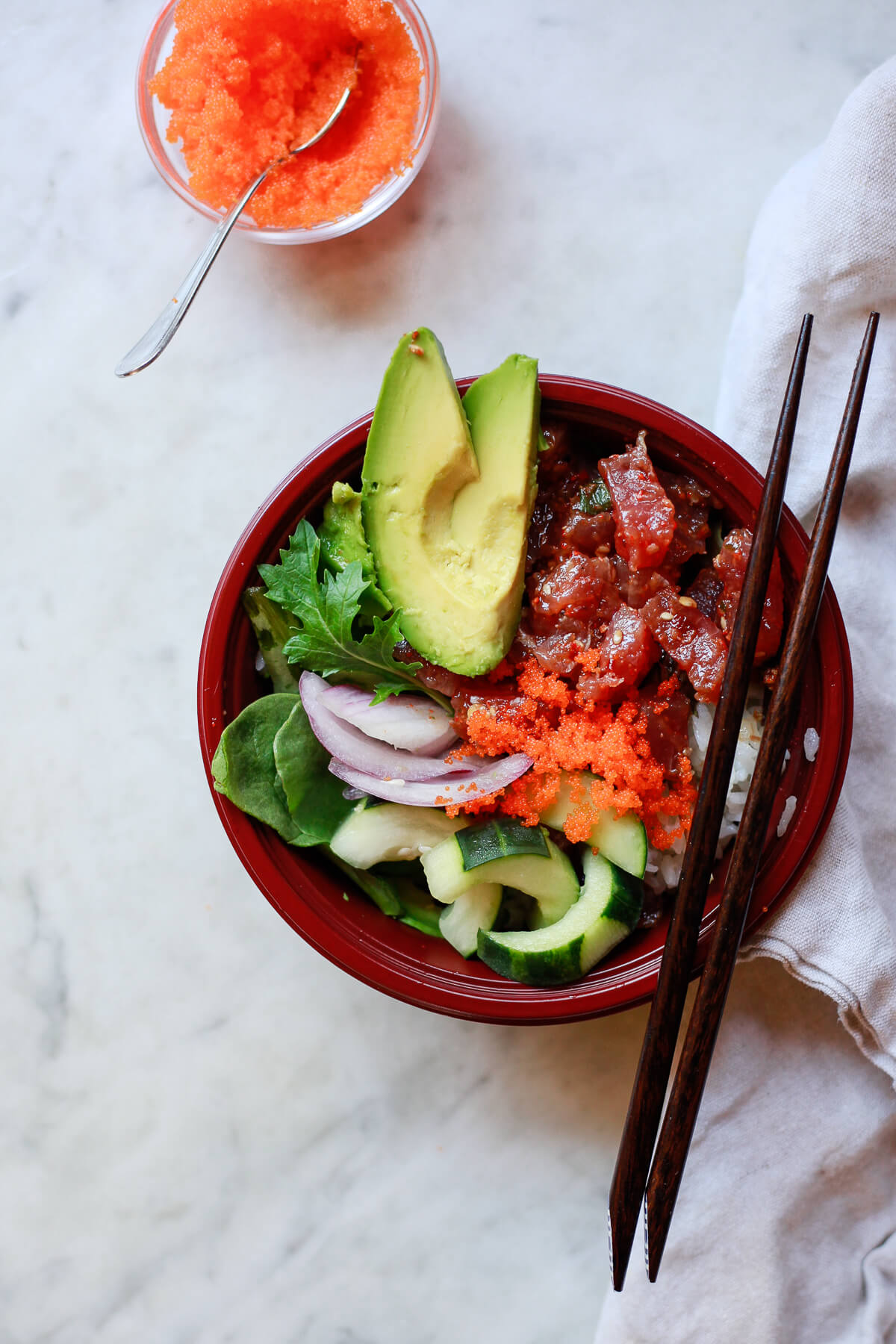 A spicy ahi poke bowl with avocado, greens, cucumber, onions, rice, and masago. 