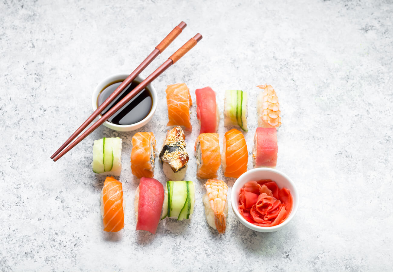 An overhead photo of a variety of nigiri including salmon, ahi, and cucumber over rice. A bowl of soy sauce sits at the left corner. 