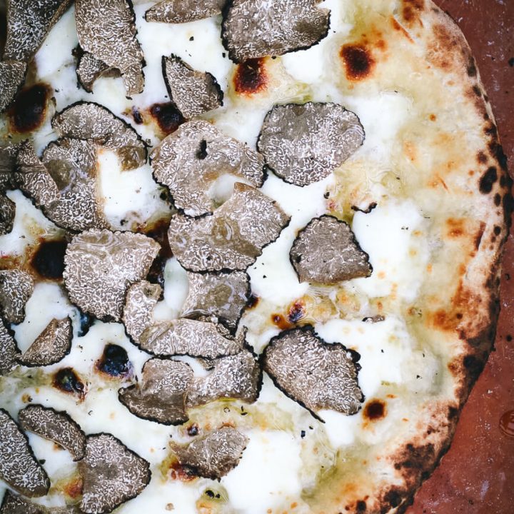 An overhead photo of a white pizza with fresh shaved black truffles.