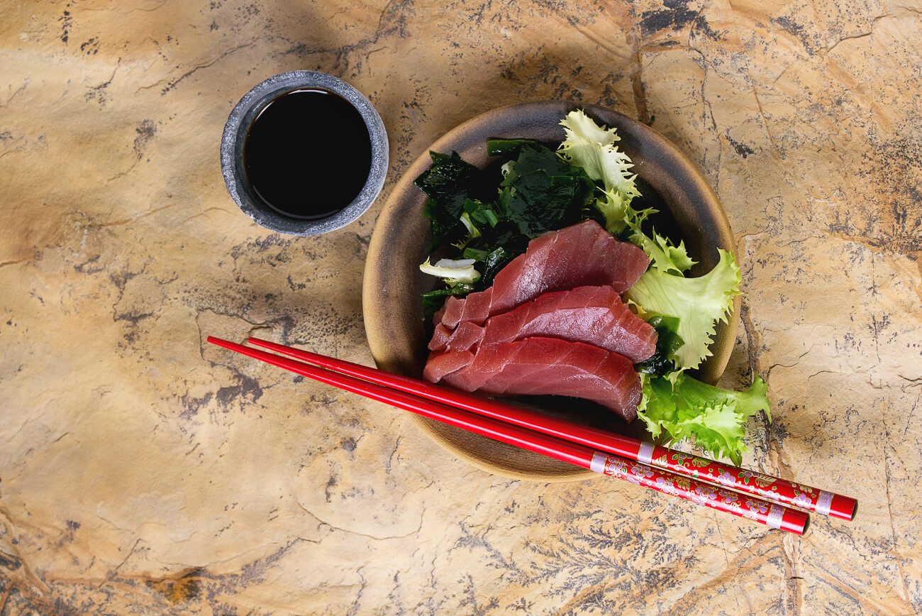 A bowl of greens topped with ahi tuna sashimi (plain raw fish). 