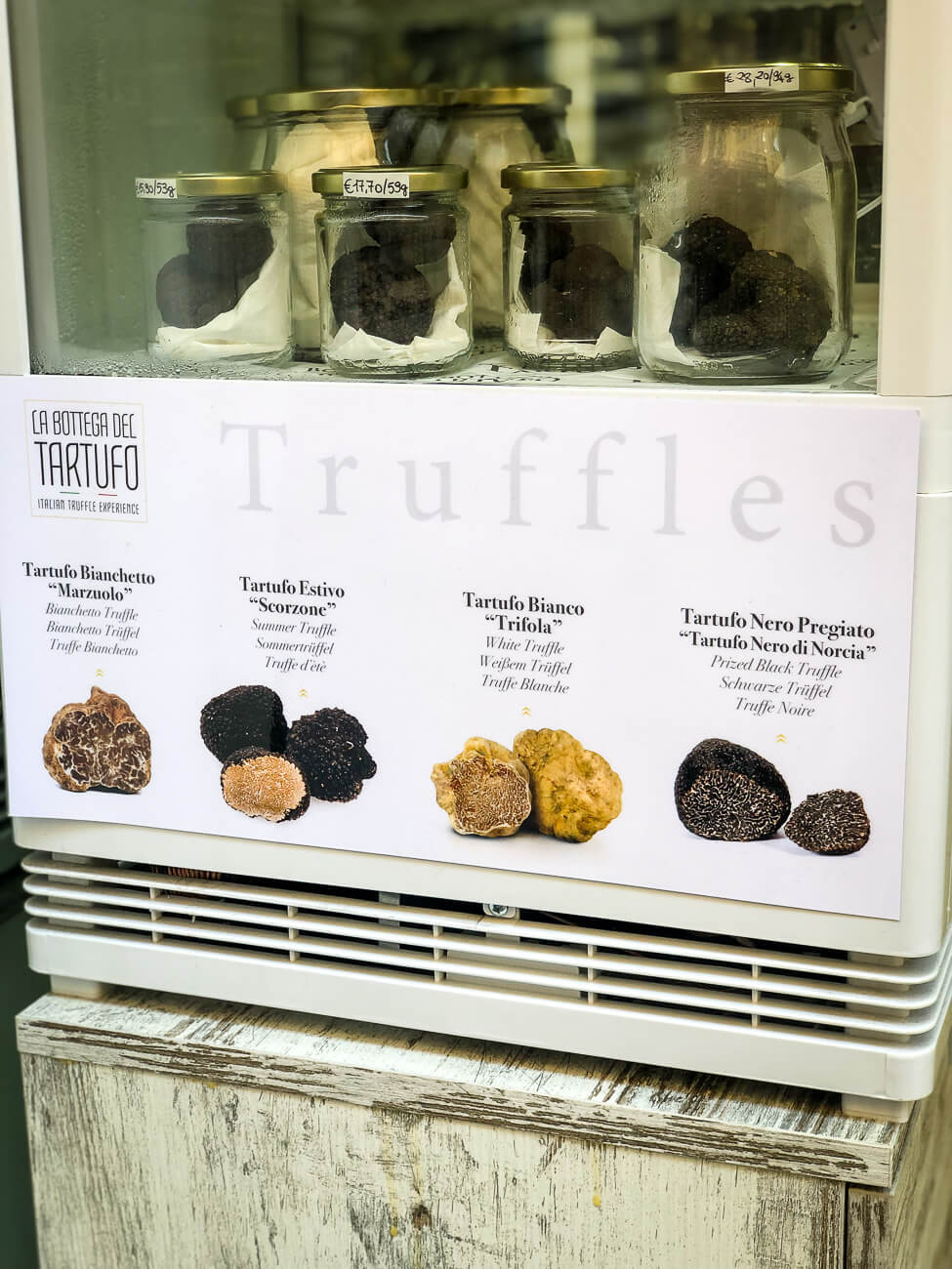 Jars of black truffles next to a sign showing four different types of Italian white and black truffles. This picture was taken in Florence Italy. 