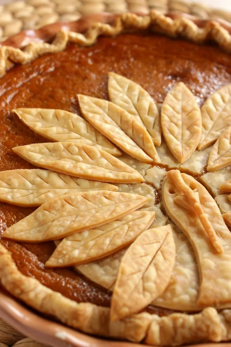 A close-up photo of a pumpkin pie decorated with a turkey made out of pie crust. 