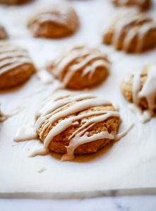 A close-up photo of vegan pumpkin cookies with vanilla icing drizzle.