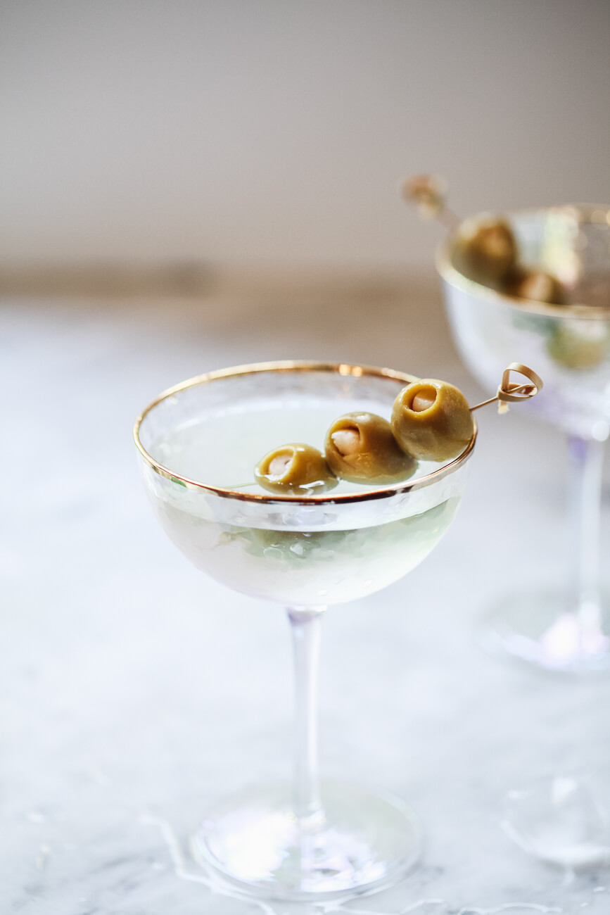 A classic Martini in an Anthropologie gold-rimmed coupe glass with three garlic-stuffed green olives. 