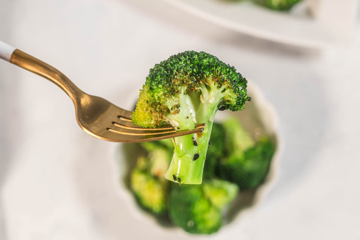 A crispy broccoli floret on a gold fork.