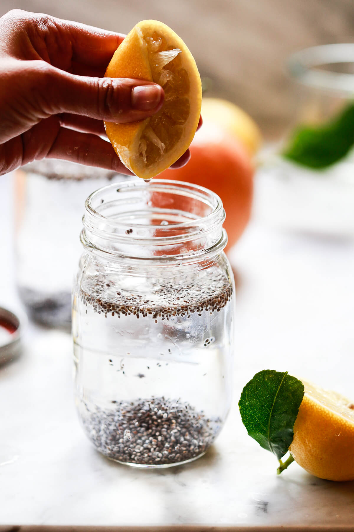 Half a lemon is squeezed over a jar of chia seeds in water drink.