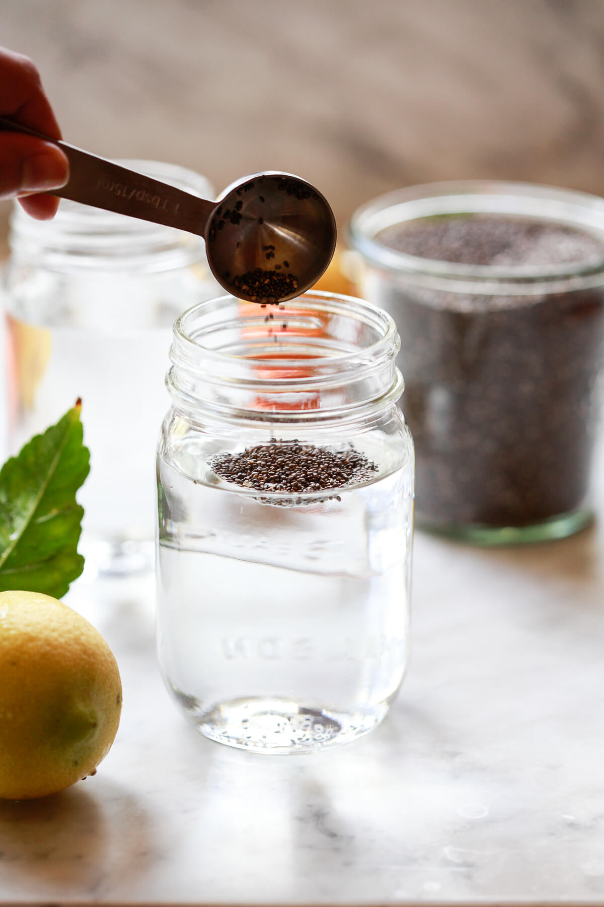A tablespoon of chia seeds is poured into a mason jar filled with water.