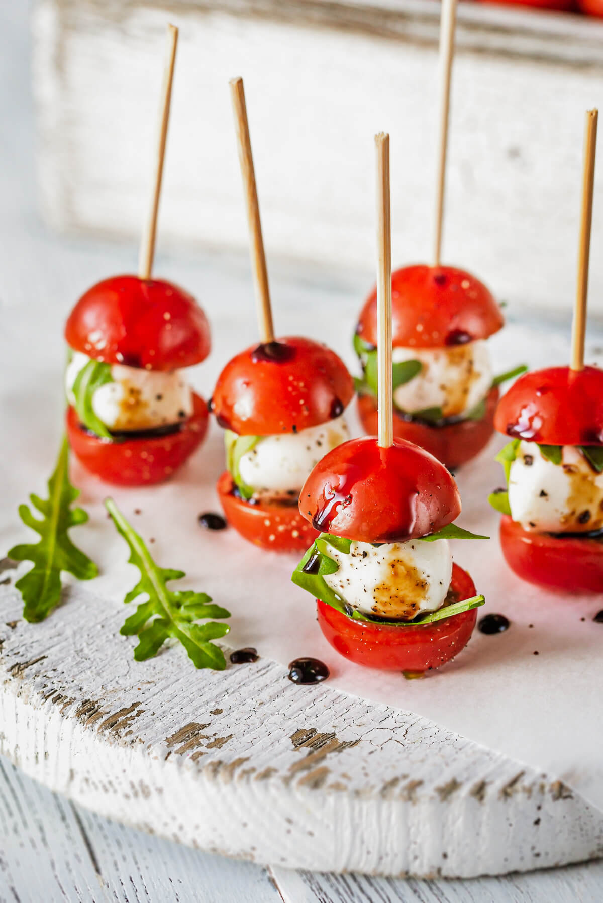 Cherry tomato and mozzarella Caprese skewers on a rustic white wooden board for an appetizer. 