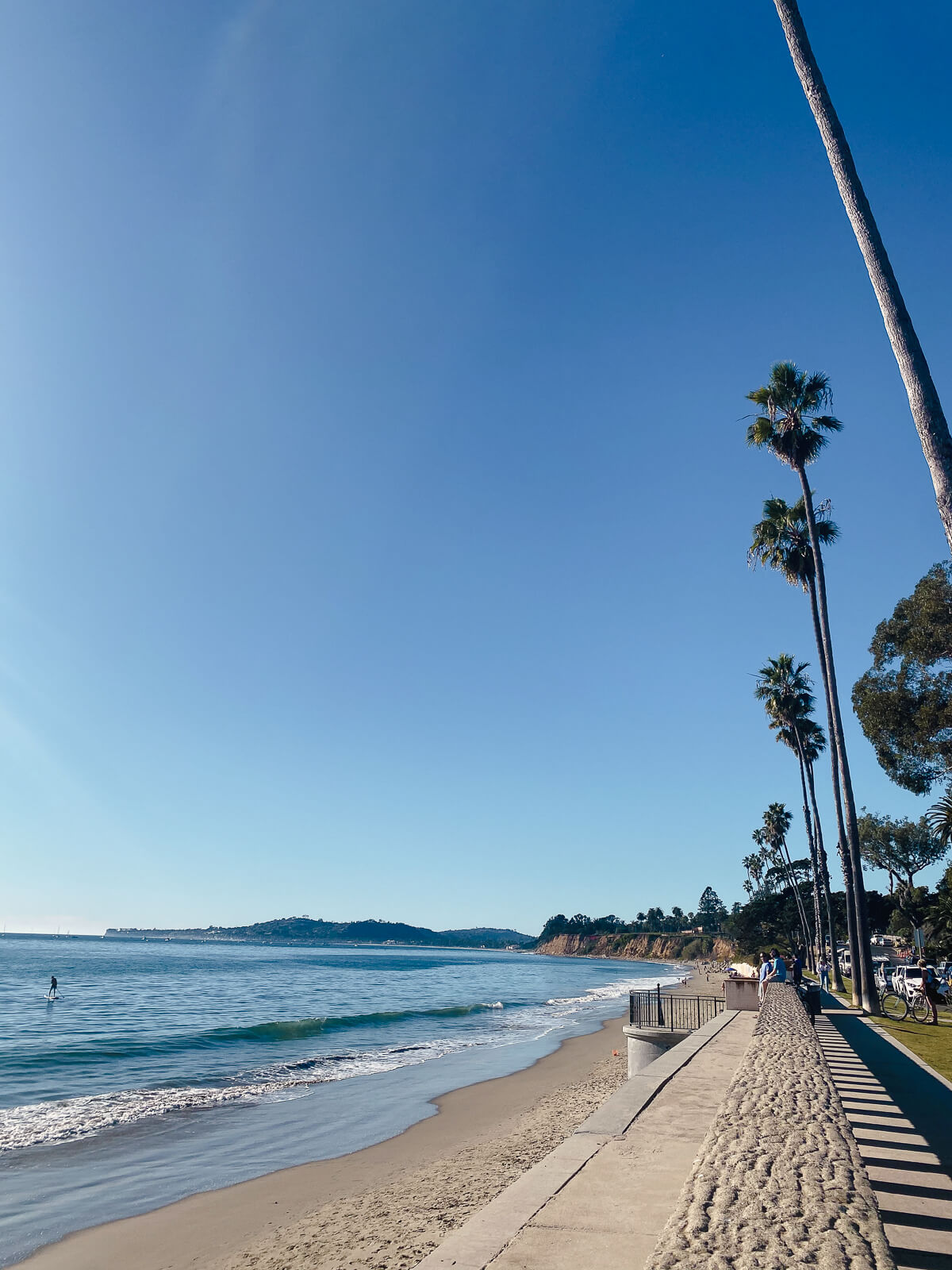 A beautiful photo of Butterfly Beach in Santa Barbara Montecito with palm trees and blue sky. 