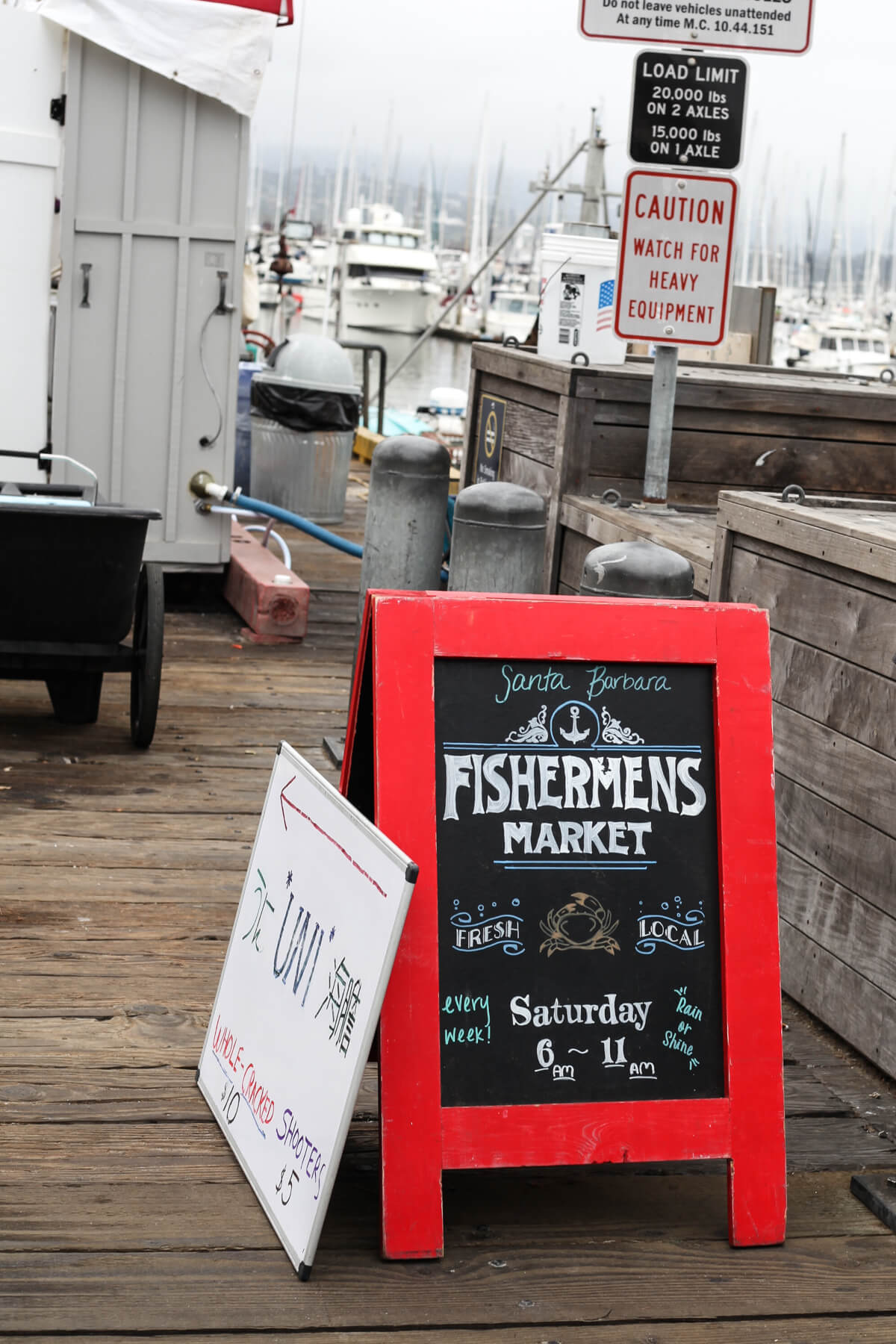 A red-framed chalkboard sign reading "Fishermen's Market" on the harbor in Santa Barbara. 